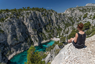 Woman sitting on rock looking at mountains