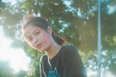 Portrait of young woman against trees