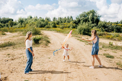 A charming little girl and her family are flying a kite. family, generation, time together, 