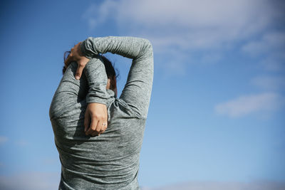 Woman stretching shoulders on the sky