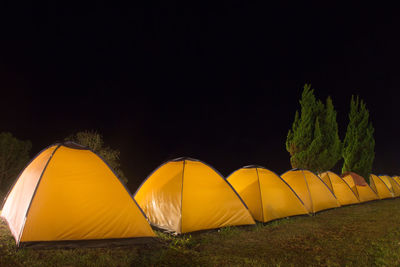 Yellow tent on field against sky at night