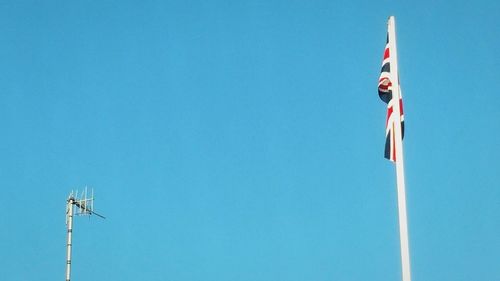 Low angle view of flags against clear blue sky