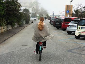 Rear view of woman riding bicycle on road