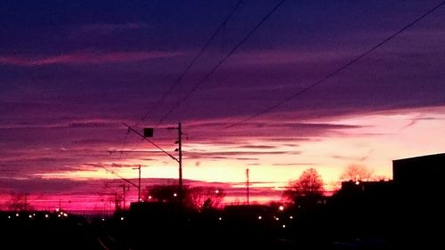 Silhouette of electricity pylon against dramatic sky