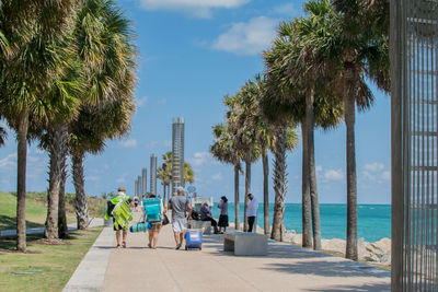 People on palm trees by sea against sky