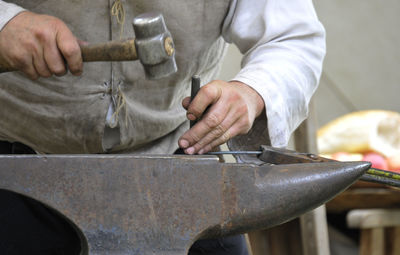 Midsection of man working on metal in workshop