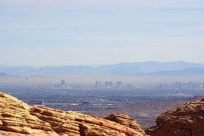 Scenic view of cityscape by mountains against sky