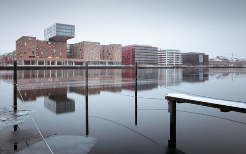 Reflection of buildings in river against clear sky