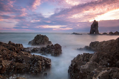 Scenic view of rocks in sea against sky during sunset
