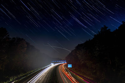 Light trails on road against sky at night