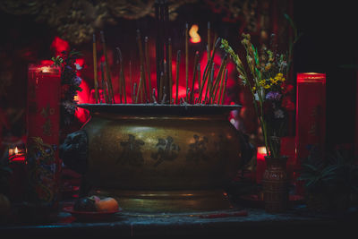 Close-up of lit candles by container at temple