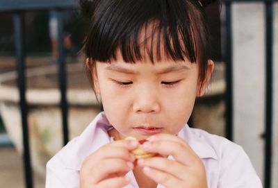 Close-up of girl eating biscuit against railing