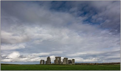 Built structure on field against cloudy sky