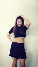 Portrait of young woman standing against white background