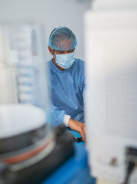 Mature man in medical uniform smiling and looking away while working in modern clinic