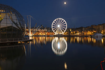 Reflection of illuminated ferris wheel in water at night