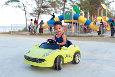 Cute baby boy driving toy car at playground
