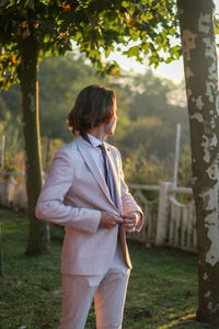 Portrait of young good looking man with long hair in boho style and elegant outfit with sunset light