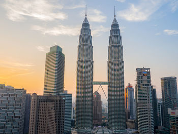 Petronas towers in city against sky during sunset