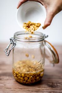 Cropped hand pouring food in jar on table