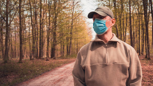 A man in a surgical mask in the autumn woods person