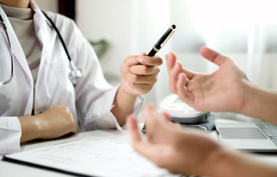 Midsection of doctor working on blueprint at office