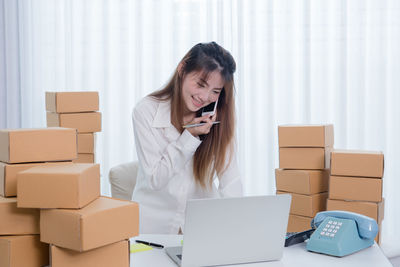 Young woman using mobile phone in box