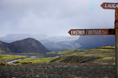 Road sign on mountain against sky