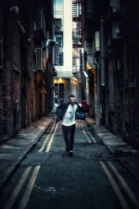 Full length of woman standing on road amidst buildings in city