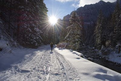 Woman walking on snow covered land against sky