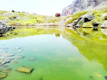 Reflection of rocks in lake against sky