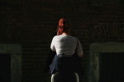 Rear view of woman standing against wall