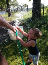 Full length of boy holding plants in water
