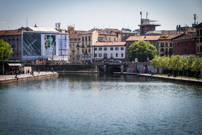 Bridge over river by buildings in city against sky