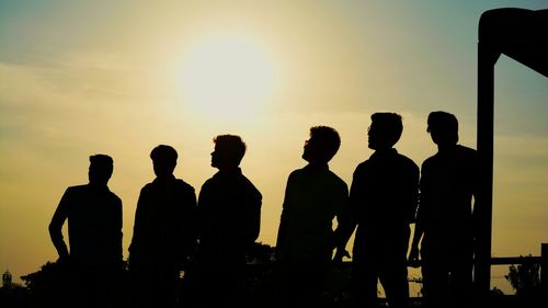 Silhouette of men against sky during sunset