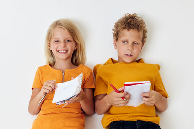 Sibling holding note pad against white background