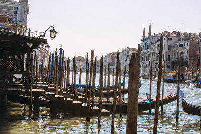 Gondolas moored by wooden posts in grand canal