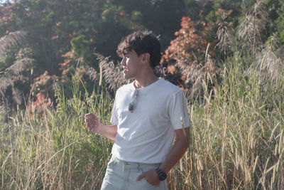 Young man looking away while standing on field