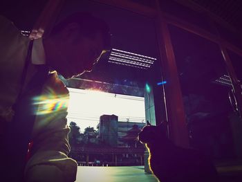 Side view of man looking through window at night