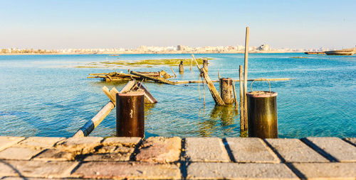 Wooden posts on sea against clear sky