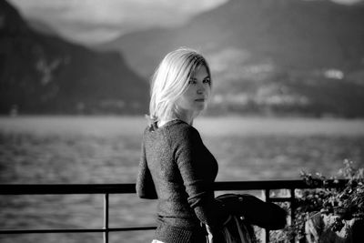 Woman standing by railing against sea