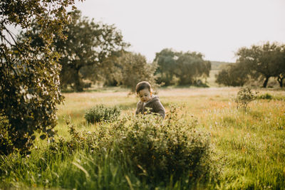 Boy standing by plant on field