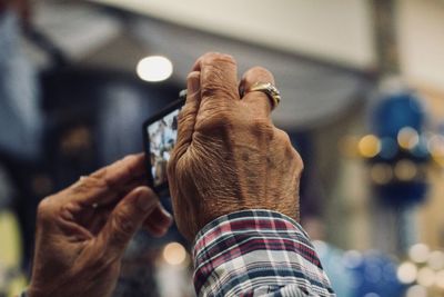 Close-up of senior person photographing through smart phone