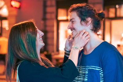 Side view of smiling couple romancing on street at night