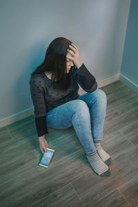 Young woman sitting on hardwood floor at home