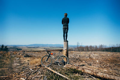 Man riding bicycle on field against clear sky