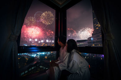 People looking at firework display during night