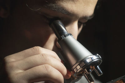 Close-up of man looking through microscope