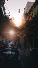 People on street amidst buildings in city during sunset