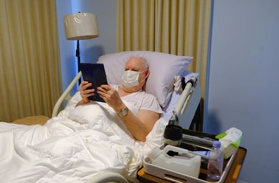Midsection of man reading book on bed at home